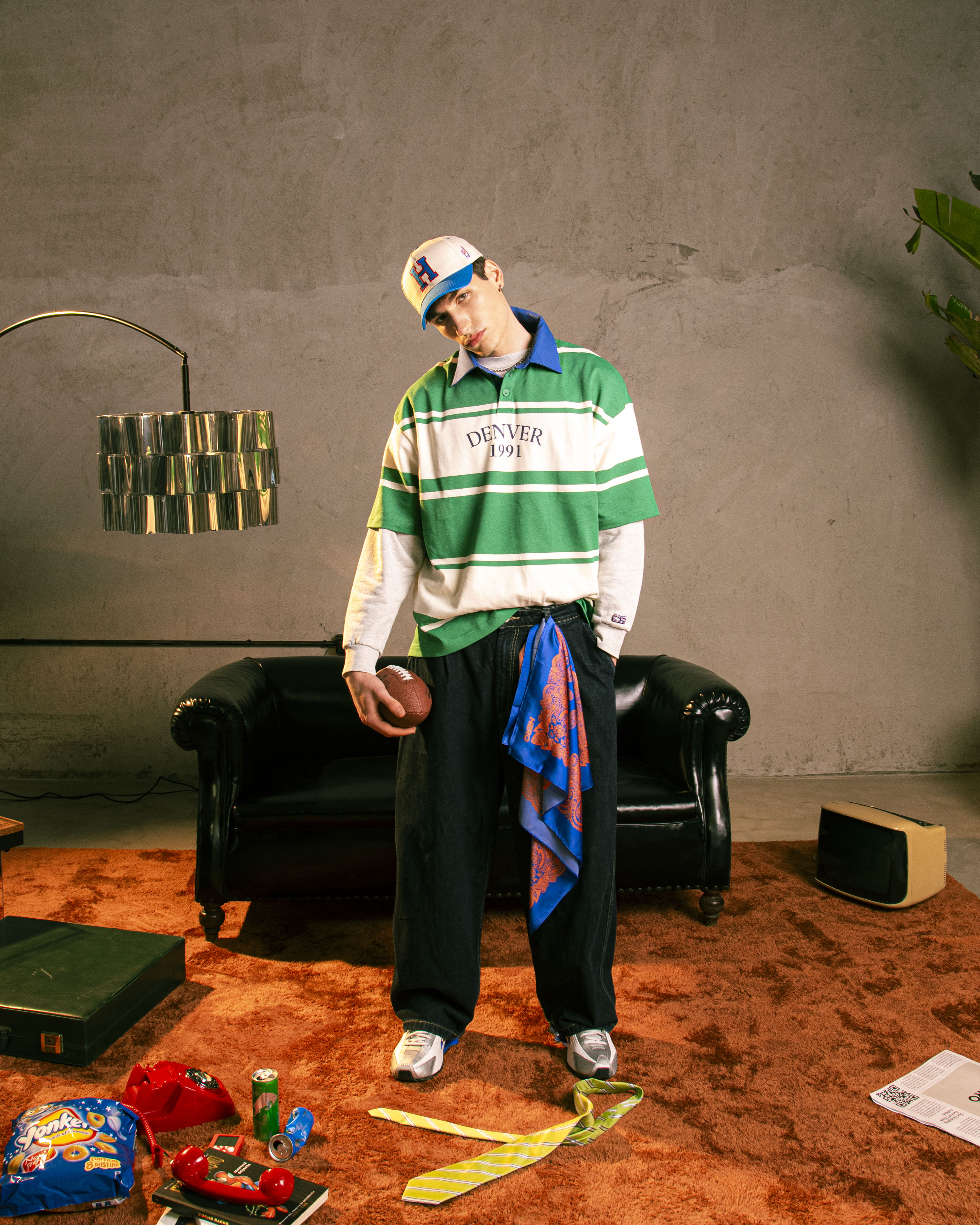 Modello streetwear con polo a righe verdi , foulard paisley e cappellino baseball bicolore HERO ricamato — stile vintage anni ’90 in set creativo HERO.
